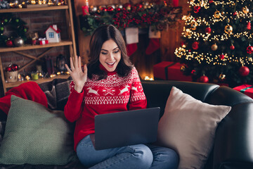 Photo of excited cheerful person sit sofa hand waving speak video call christmastime atmosphere indoors