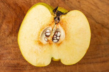 Quince fruit half, close up on a defocused wood board