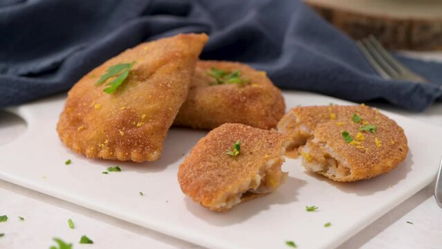 Meat patties and parsley leaves on white ceramic dishes in a kitchen counter top.