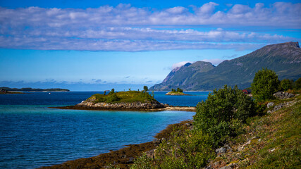 panorama of the landscape of the senja island, northern norway, small colourful houses on the seashore under huge rocks and cliffs, paradise beaches in rocky fjords