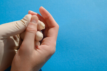 The doctor examines the affected nails - onycholysis, close-up on a blue background. 