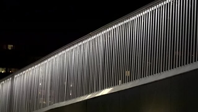 Copenhagen, Denmark, A fence and a bicyclist at night on the Bicycle Highway, or Cykelslangen, in the Fisketorv district.