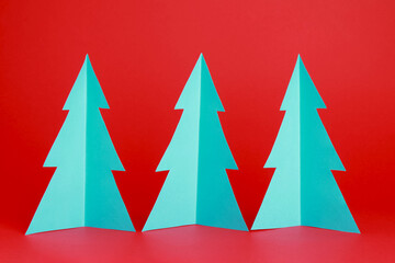 Origami paper Christmas tree on red color background. Winter background. Design elements for holiday Christmas card. Christmas Xmas New Year concept. Close-up. Front view