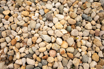 Stones of various sizes in gray, white, yellow, orange and light purple. Some are smooth and round. Others are jagged and irregular.