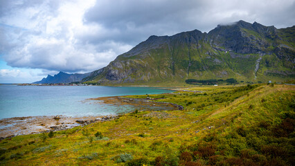 Fototapeta na wymiar panorama of the landscape of the lofoten islands, norway, small colourful houses on the seashore under huge rocks and cliffs, paradise beaches in rocky fjords