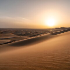 Desert sand dunes with sun shining above clouds on the horizon