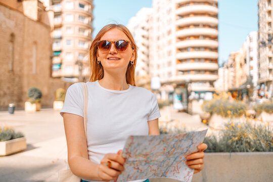Young traveller woman walking on old town holding tourist map looking for direction in the city. Valencia, Spain travel summer tourism holiday vacation background. 