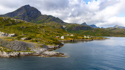 Plakat the harsh landscape of the norwegian fjords on the Lofoten islands, small houses by the sea with huge mountains above them