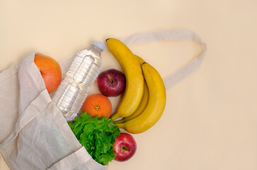 Eco fabric bag, grocery shopping, healthy lifestyle. Fruits and a bottle of water in a linen bag. Cotton shopping bag. zero waste concept.