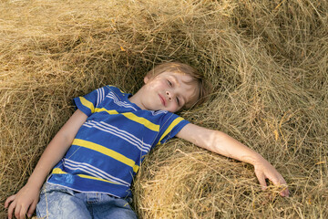 The guy is resting, lying on the hay