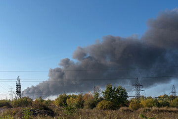 A large column of smoke rises over the electrical pylons from an explosion of a Russian missile