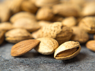 shelled almonds on a dark stone table with a wooden spoon and a bowl. Almonds in a wooden bowl.