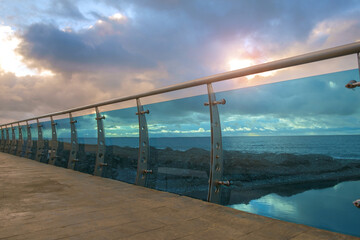 Modern bridge construction detail made by steel and glass on the beach with cloudy sky background