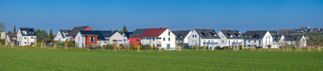 Fototapeta na wymiar Reihenhäuser und Doppelhaushälften am Rand eines Feldes in einer Neubausiedlung in einem Vorort von Frankfurt am Main bei sonnigem Wetter