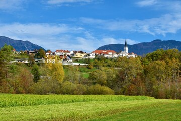 View of the town of Radovljica in Gorenjska, Slovenia with a green field in front and forest...