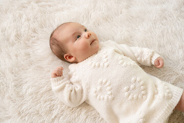 New born baby girl sleeping on texture blanket, lying on blanket, opened eyes, white dress