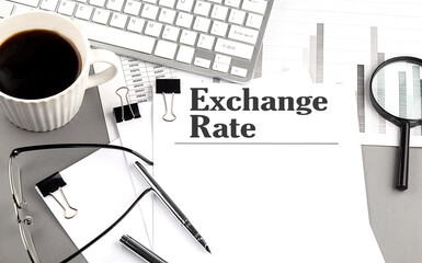EXCHANGE RATES text on a paper with magnifier, coffee and keyboard on grey background