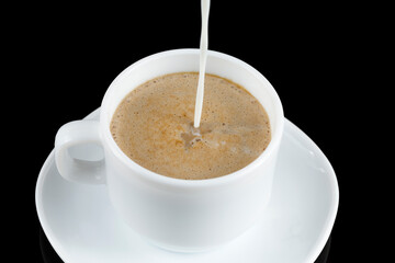 Coffee with milk. Milk is poured into a cup with coffee. White cup of coffee