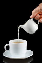 Coffee with milk. Milk is poured into a cup with coffee.