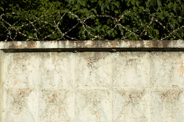 Barbed wire on fence. Old fence. White concrete slab.