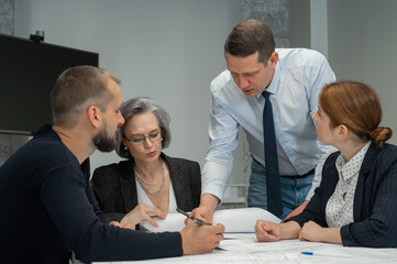 The boss gives instructions to three employees in the office conference room. Brainstorming engineers and architects. 