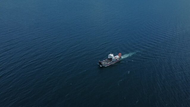 4k Top view of ship moves on lake outdoors irrl. Aerial of large vessel moving through blue waters and delivering cargo in open air. Beautiful drone picture of modern transportation and natural