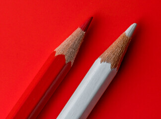 two red and white pencils seen closely and placed on a red background