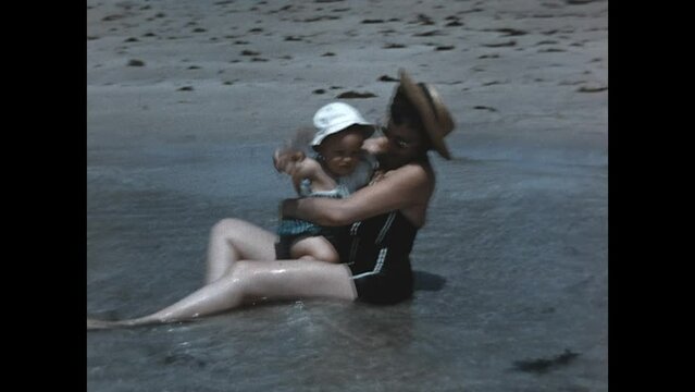 Sitting on the Shore 1960 - A mother sits on the shore and plays in the water with her young daughter in Miami, Florida, 1960.