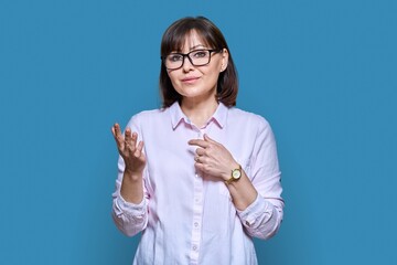 Talking gesturing woman looking at camera on blue studio background