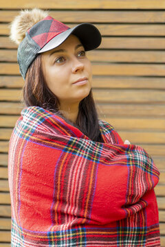 Portrait of a beautiful woman 40-45 years old in a plaid and cap on the background of a wooden fence.