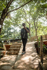 black man wearing a kimono posing for a portrait while holding a tea cup in a garden