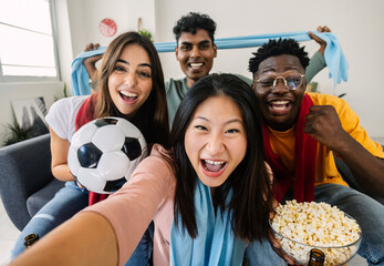 Excited multiracial young friends taking selfie portrait together with phone while watching football match on television at home - Home party and soccer championship concept - obrazy, fototapety, plakaty