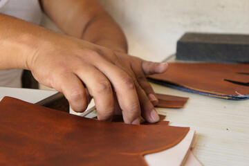 Acercamiento a Manos de Artesano talabartero trabajando en la confección de botas de cuero en Pastores Antigua Guatemala, 