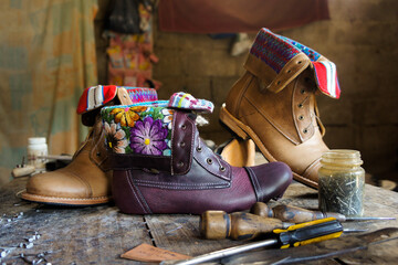 Taller artesanal de zapatos, botas y botines en talabartería con diseños de textiles típicos de Guatemala, en el municipio de Pastores, Antigua Guatemala. - obrazy, fototapety, plakaty