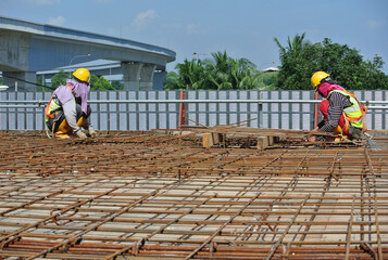 MALACCA, MALAYSIA -MARCH 30, 2016: Construction workers fabricating steel reinforcement bar at the construction site in Malacca, Malaysia. The reinforcement bar was ties together using tiny wire.  