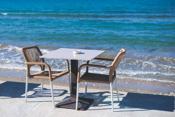 Restaurant terrace by the sea, seaside view cafe on the beach, empty chairs and tables Ionian sea shore, Greece, blue sea with crystal clear water