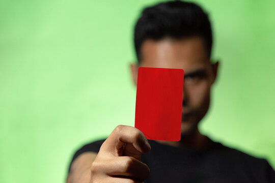 
Hombre mostrando tarjeta roja o amarilla en fondo verde concepto de &aacute;rbitro futbol o deporte en general. Amonestaci&oacute;n deportiva.
