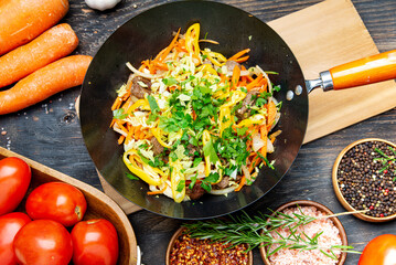 vegetables stewed with meat in a wok. a variety of vegetables and spices for cooking stews on the table..