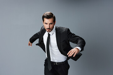 Man business happy in jacket and shirt jumping and running on gray background raised hands up...