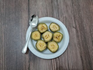 Ripe banana slices with green skin served in a white container