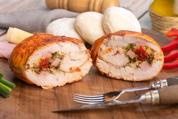 chicken roll stuffed with vegetables and ham and cheese with homemade bread on a round wooden plate with decorating ingredients - obrazy, fototapety, plakaty