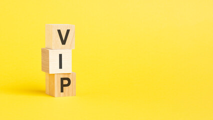 text vip on wooden cubes on yellow background. abbreviation of 'Very Important Person'. square wood blocks