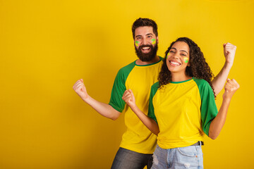 couple of brazil soccer supporters, dressed in the colors of the nation, black woman, caucasian...