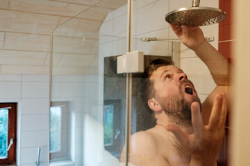 Man is angry in the shower because the water stopped flowing due to a breakdown or economy.
