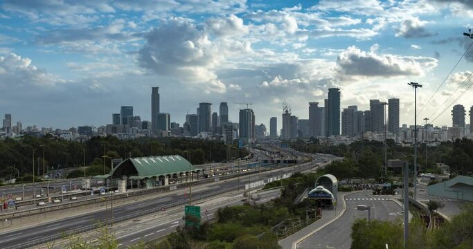 Time lapse of cars driving via ayalon road, in front of the cityscape of ramat gan and Tel Aviv cities with moving blue cloudy skies, Israel