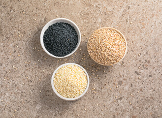Set with different sesame seeds on stone background. top view.