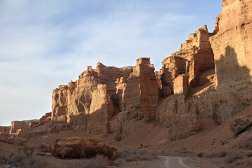 Fototapeta premium A wall of beautiful relief towers in the sandy-clay canyon Charyn against the background of a sky with clouds, sunny