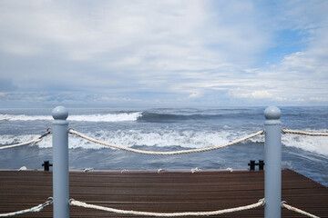 Picturesque view of sea with waves behind pier fence