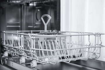 Open clean empty dishwasher in kitchen, closeup