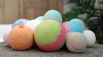 Many different colorful bath bombs on wicker mat in bathroom, closeup